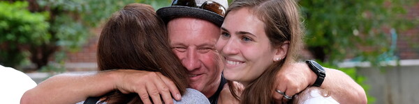 A father says good by to his daughters with a hug.