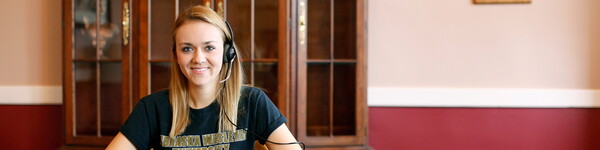 A femail NWU student wearing a headset.